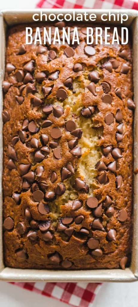 Loaf of chocolate chip banana bread sliced on a wooden board