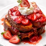 Delicious BAKED STRAWBERRIES AND CREAM FRENCH TOAST with fresh strawberries and whipped cream.