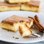 Mexican Churro Cheesecake Bars with flaky crust and creamy filling topped with cinnamon sugar.
